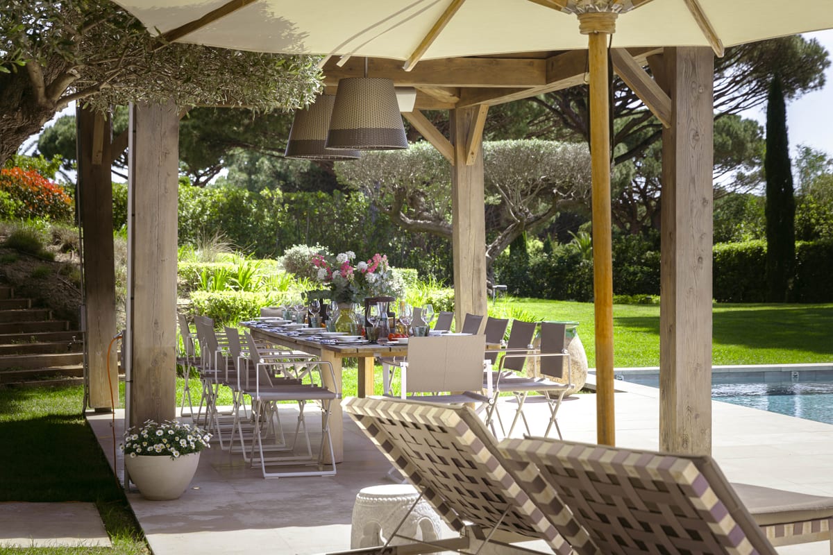 The dining table and loungers seen between the pergola posts, the pool to the right.