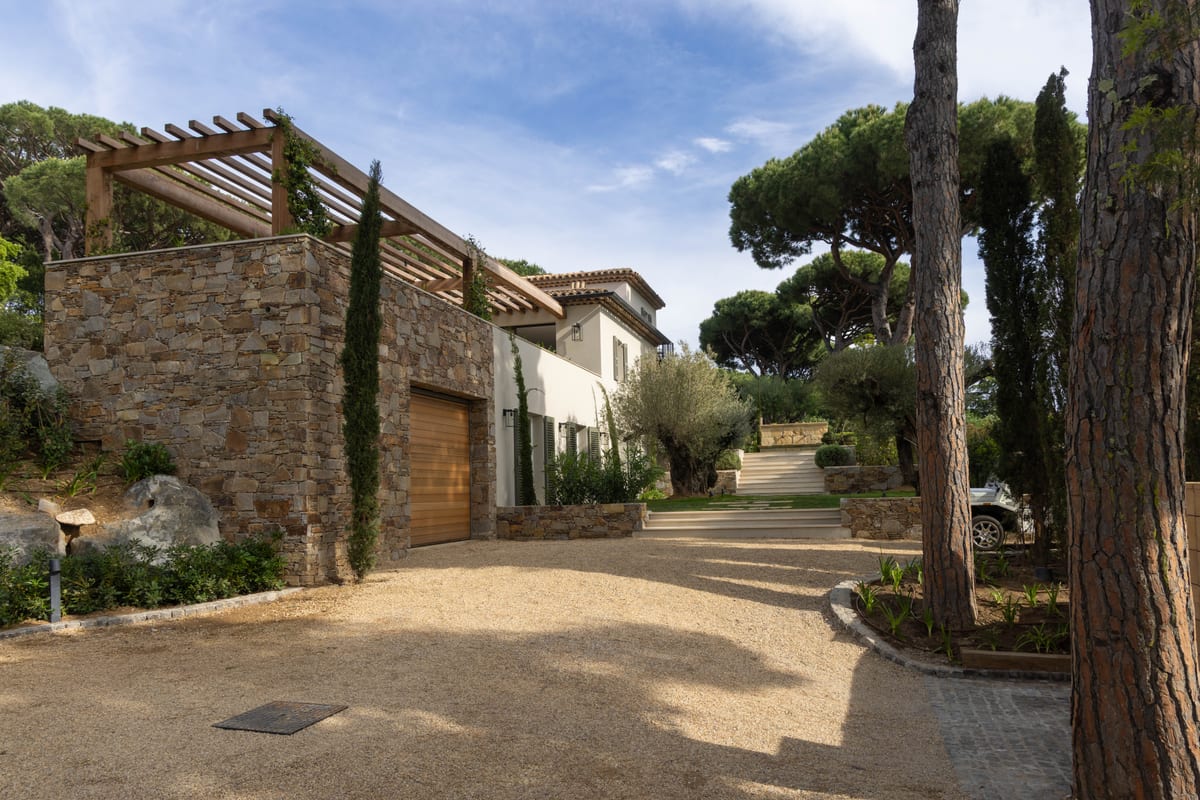 The approach to the house: a gravel drive between a dry-stone wall and tall pines.